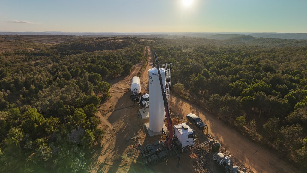 Reservatório metálico tubular alto branco da Fortmetal sendo instalado em área rural com auxílio de caminhão guindaste